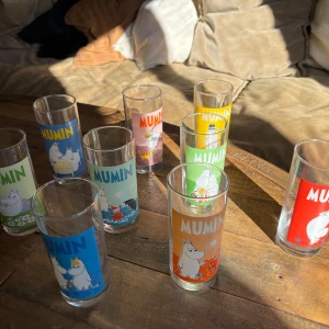 Färgglada Mumin-glas - Säljer en samling av nio färgglada Mumin-glas med olika motiv och färger. Perfekta för Mumin-fans och samlare. Glasen har motiv i blått, grönt, rött, gult och orange med olika Mumin-karaktärer. En av glasen är skadade på kanten.