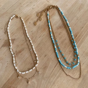 Somriga halsband🫶 - Säljer 2 set med halsband💗 Det ena har vita pärlor och det andra blå pärlor, båda med guldkedjor. Perfekt för att lägga till en färgklick till din outfit nu till sommaren och våren🫶100 kr för båda paren☺️