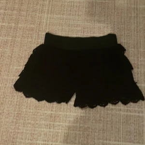 Svarta spets shorts - Snygga svarta shorts med volanger och spetsdetaljer.har aldrig andvänt dem.dem finns i beach,vit,svart. Perfekt för en avslappnad men lite uppkläd look. Den har en elastisk midja för bekväm passform.obs:kommer skicka dem 5-7 april❤️
