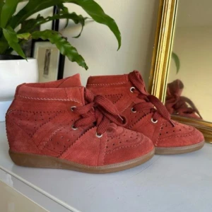 Isabel marant skor - Snygga röda sneakers i mocka med kilklack och snörning. Perfekta för en trendig look med perforerade detaljer och en bekväm gummisula. Köpt begagnat men använt av mig en gång, inge defekter, som nya 💕💕