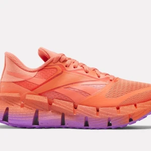 Orange och lila sneakers från Reebok - Snygga och färgglada sneakers från Reebok i en härlig orange nyans med lila detaljer på sulan. Skorna har snörning och en ventilerande ovandel i syntetmaterial. Perfekta för löpturer eller en färgstark vardagslook. Använda vudxett tillfälle inomhus. 