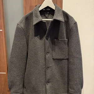 Grå overshirt från Zara - Säljer en stilren grå overshirt från Zara. Funkar perfekt i vår vädret. Knappt använd och säljs för att den var för stor. Nypris 1299kr