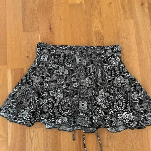 Svart och vit blommig kjol - Söt kjol till sommaren!! Svart och vit blommigt mönster med snören i midjan💘💘 Storlek S från Zara