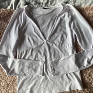 Vit långärmad topp - Säljer en stilren vit långärmad topp med v-ringad design. Jätteskönt material nästan lite silkes. Strl S.Aldrig använd
