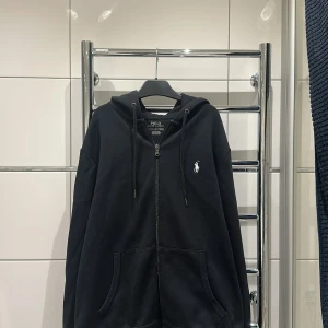 Polo ralph louren zip hoodie  - Jag säljer denna svarta stilrena polo ralph louren zip hoodie för att den inte kommer till andvänding. Den är i storlek s ,Skicket är 8,5/10, tröjan är köpt på nk i Göteborg (kvitto finns) priset kan diskuteras 