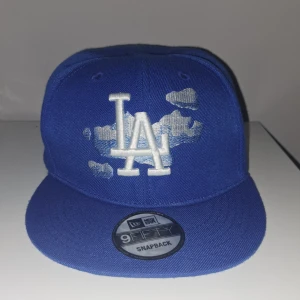 Blå new era keps - Säljer min blåa new era keps som är perfekt till sommaren. Kepsen har ett unikt motiv där frame. Kepsen är nästan aldrig använd och är i väldigt bra skick. Kepsen har justerbar storlek. Kan gå ner i pris vid snabb affär!