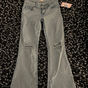 Ljusblå bootcut jeans med slitningar - Snygga ljusblå bootcut jeans med slitningar på knäna och broderad detalj på bakfickan. Aldrig använda, helt nytt skick.