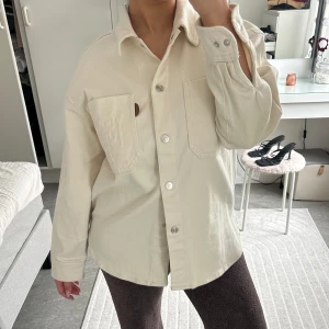 Beige overshirt med fickor - Säljer en stilren beige overshirt med långa ärmar och knappar framtill. Skjortan har två stora bröstfickor och en avslappnad passform. Perfekt för lager-på-lager-stil. Köpt i Turkiet 🌸