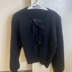 Svart kofta med knytband - Jättefin långärmad stickad tröja som man kan göra två knutar på och öppna de om man vill och styla den på många olika sätt! Använt den en enstaka gång och köpt den från shein. Jätte skönt material men har enkelt att bli elektriskt när man tar på sig den annars är den perfekt och felfri💞 priset går alltid att diskutera😇