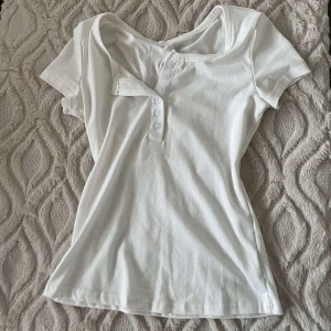 Vit kortärmad topp från Shein - Säljer en vit kortärmad topp från Shein i storlek XS. Toppen har en knappdetalj framtill och är tillverkad i en mjukt material som är skön mot kroppen. Tröjan är lite genomskinlig. Har andvänt kanske 1-2 gånger
