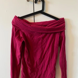 Vinröd offshoulder topp från Ralph Lauren - Säljer en elegant vinröd offshoulder topp från Ralph Lauren. Toppen har långa ärmar och en stilren design som passar perfekt för en kväll ute. Perfekt för att ge din outfit en touch av lyx.