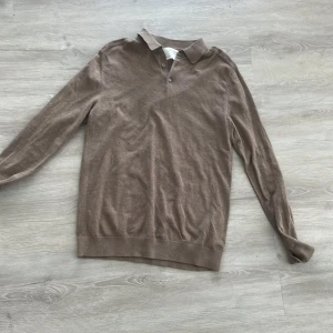 Brun pikétröja från Selected Homme - Säljer en stilren brun pikétröja från Selected Homme. Tröjan har långa ärmar och en klassisk krage med knappar. Perfekt för en avslappnad men ändå snygg look.