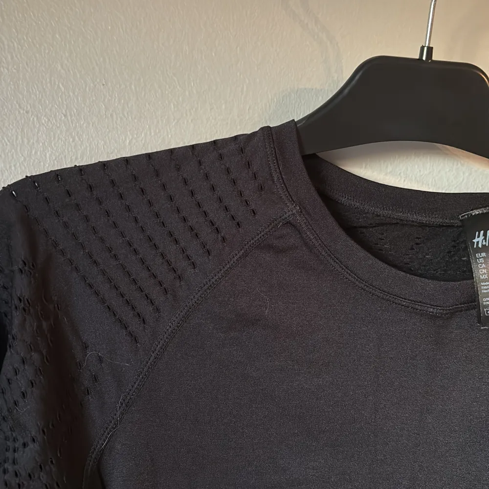 Snygg svart långärmad träningströja från H&M med coola perforerade detaljer på ärmar och rygg. Perfekt för en stilren look vid all träning;) Tröjan har en rund halsringning och är tillverkad i ett stretchigt material för extra komfort. Köparen står för eventuell fraktkostnad:)). Neuletakit & Villapaidat.