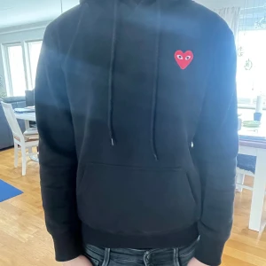 Svart hoodie från Comme des Garçons - Säljer en svart cdg hoodie med rött hjärta.  Storleken är M men sitter lite mer som S. Tveka inte på att fråga vid funderingar. Jag är 177 och väger ca 68