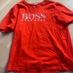 Orange t-shirt från Hugo Boss - Säljer nu denna tröja eftersom den inte passar längre. Varan är i bra i skick. Tröjan är i barn storlek( 12 år eller Xs)
