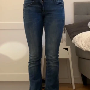 Blå bootcut jeans - Super snygga blå bootcut jeans med låg midja med W26 och längd 30 (storlek S). Fint märke och därför har bra kvalitet. Har andvänds några gånger men är tyvärr för små för mig nu. Orginalpris på jeans är 1095kr. Priset kan diskuteras! 