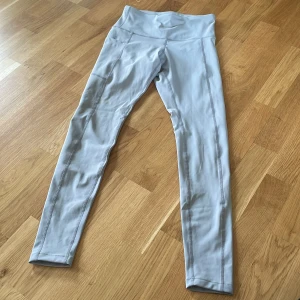 Ljusgrå leggings - Säljer ett par ljusgrå leggings med hög midja. De är tillverkade i ett mjukt och stretchigt material som passar perfekt för träning eller en avslappnad dag. Leggingsen har en enkel design utan mönster eller detaljer.