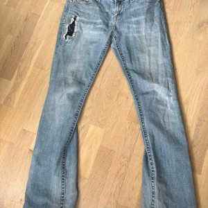 Miss Me ljusblå bootcut jeans strl 30 - Säljer ett par ljusblå jeans från Miss Me i bootcut-modell. Jeansen har slitningar och hål på låret, snygga broderade bakfickor med detaljer och klassisk femficksdesign. Materialet är jeans med stretch och de har låg midja. 