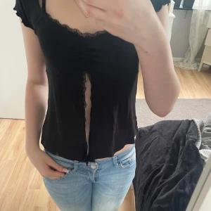 Svart topp från Gina Tricot - Säljer en svart croppad topp från Gina Tricot med spetsdetaljer längs halsringningen och framtill. Helt oanvänd i storlek S❤️