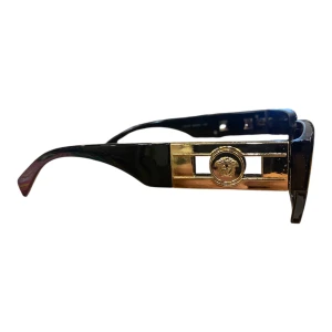 Svarta solglasögon med guld - Riktigt feta svarta solglasögon med breda bågar och ikonisk guldig Medusa-detalj på sidorna. Rektangulär form och mörka glas ger en lyxig och edgy vibe. Perfekta för dig som vill sticka ut och köra på en statement-look.