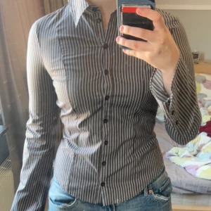 Brun och vit randig skjorta - Säljer en brun skjorta med vita ränder och klassisk krage. Sitter tight och har en figurnära passform, perfekt till jeans eller kostymbyxor. Säljer då den är för liten för mig. Aldrig använd. Prislappen finns kvar. 
