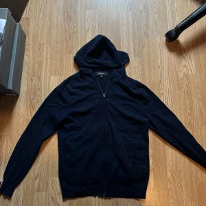 Mörkblå kashmirhoodie från Lawrence Grey - Säljer en riktigt mjuk och lyxig mörkblå hoodie från Lawrence Grey i 100% kashmir. Tröjan har en lite tightare passform, alltså inte särskilt baggy. Perfekt för sommarkvällar eller att bara ha hemma! Säljer pga för liten. Hör av er vid frågor/funderingar!