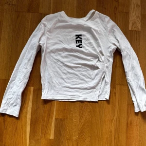 Vit långärmad tröja med tryck från Zara - Säljer en vit långärmad tröja från Zara med svart texttryck 'KEY' på bröstet. Tröjan har en rak passform och är tillverkad i mjuk bomull. Perfekt till en enkel och stilren look.