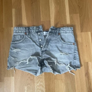 Gråa slitna jeansshorts med hög midja - Gråa jeansshorts från Zara  med hög midja och  slitna detaljer framtill. Säljer pga av att de är för små. Köparen står för frakt 