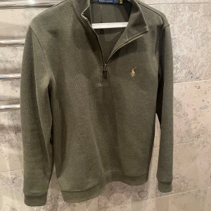  Polo Ralph Lauren tröja  - Säljer en olivgrön långärmad tröja från Polo Ralph Lauren med halv dragkedja och broderad logga på bröstet. Den är i bra skick utan defekter. Perfekt för en avslappnad och stilren look. Passar mig som är ungefär 181cm lång. Skriv privat om ni har några funderingar!