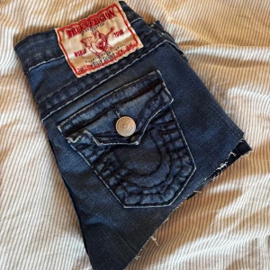 Mörkblå jeansshorts från True Religion - Säljer ett par mörkblå lågmidjade jeansshorts från True Religion stora fickor bak med dekorativa sömmar och silverfärgade knappar. Klassisk femficksmodell och låg midja. Storlek 26. Perfekta för sommaren!❣️🥂