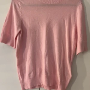 Ljusrosa kortärmad tröja 157 XS - Supersöt ljusrosa tröja från 157 i storlek XS. Tröjan har korta ärmar, rund halsringning och är gjord i ett mjukt, tunt material som känns skönt mot huden. Perfekt för vår och sommar när du vill ha en enkel men stilren look.