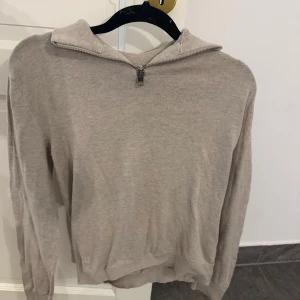 Beige stickad tröja med half zip - Beige stickad tröja med halv zip i märket Jack and Jones. Långärmad modell med mjukt material och enkel, stilren look. Perfekt för lager-på-lager och chill dagar. Passar dig som gillar en clean och avslappnad vibe.