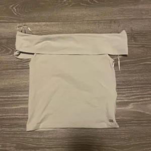 Beige tubtopp från Pull&Bear - Säljer en stilren beige tubtopp från Pull&Bear, Pacific Republic Teen Department. Toppen är axelbandslös och har en enkel, clean design som är lätt att matcha. Perfekt för varma dagar eller lager-på-lager. Gjord i mjuk bomull för skön känsla.