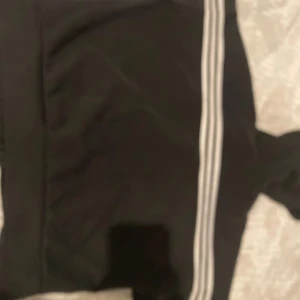 Svarta Adidas mjukisbyxor XS - Svarta kofta  från Adidas i storlek XS med klassiska vita ränder längs sidorna. 
