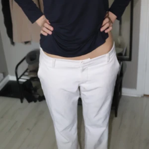 Vita kostymbyxor från Bikbok - Snygga vita populära kostymbyxor från bikbok. Klassisk rak passform och låg midja. Byxorna har diskreta fickor bak och bälteshällor i midjan. Perfekta för en stilren och clean look, framförallt på sommarn.