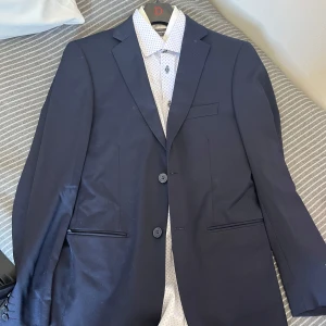 Mörkblå kostym från Dressmann - Säljer en stilren mörkblå kostym från Dressmann. Kavaj och byxor.