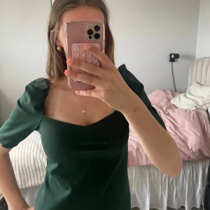 Mörkgrön topp med puffärmar - Säljer en mörkgrön topp med snygga puffärmar och fyrkantig urringning. Väldigt bra skick och knappt använd