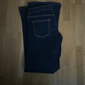 Nya Weekday Jeans, storlek 32/34 – Aldrig använda! - Säljer ett par mörkblå jeans med bootcut passform och tydliga kontrastsömmar. Jeansen har klassiska fyra fickor och låg midjade. Perfekta för dig som gillar en tidlös stil med lite utsvängda ben. 