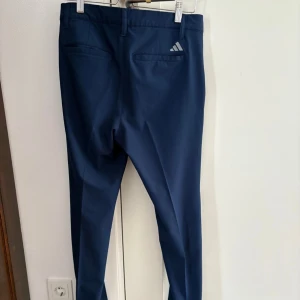 GOLF adidas golfbyxor - Ett par mörkblå golfbyxor från Adidas. Spliter nya golfbyxor. Köpte alldeles för små. Storlek 28/30.