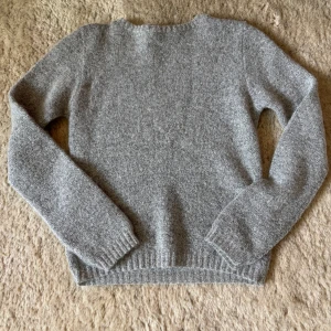 Grå stickad tröja från Filippa K - Mysig grå stickad tröja från Filippa K. Klassisk modell med rund halsringning och långa ärmar. Perfekt för kyliga dagar och enkel att matcha med olika outfits.