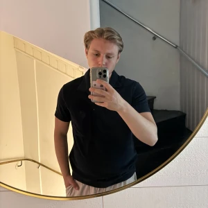 Mörkblå pikétröja från H&M - Säljer en mörkblå pikétröja från H&M i regular fit. Tröjan har korta ärmar, klassisk krage och knappar framtill. Perfekt för en stilren och enkel look.