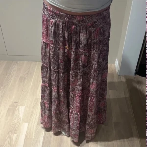 Rosa/lila långkjol från Designbysi - Säljer en långkjol i rosa och lila toner med blommigt mönster från Designbysi som inte går att köpa längre 😋😍. Kjolen är i storlek Xs-S och är använd en gång utan defekter! ☺️💗