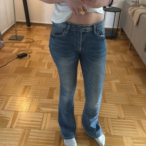 Blå bootcut jeans med rå kant - Snygga blå bootcut jeans med mellan midja. Jeansen har klassisk femficksdesign och är tillverkade i stretchig denim för en bekväm passform. Perfekta för dig som gillar en avslappnad men trendig look. Dem är lite slitna ner till men det är inget mat tänker på. Vet inte vart dem är ifrån eller storlek men dem passar mig som är 158 cm lång.