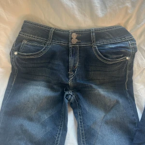 Mörkblå bootcut jeans - Snygga mörkblå jeans med vita kontrastsömmar och dekorativa bakfickor. De har en klassisk femficksdesign och stängs med dragkedja och 2 knappar. Köpta i USA🩷