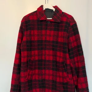 Peak Performance wool shirt L - Snygg röd och svart rutig jacka från Peak Performance. Perfekt för kyligare dagar med sin stilrena design och bekväma passform. Knappt använd, nypris 2000 kr. 
