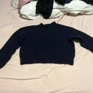Mörkblå stickad tröja från Lindex - Säljer en mysig mörkblå stickad tröja från Lindex. Tröjan har en enkel design med långa ärmar och en rund halsringning. Perfekt för kyliga dagar. Passar bra till både jeans och kjol.