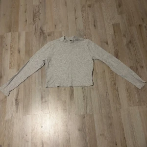 Grå ribbad polotröja från Bik Bok - Säljer en stilren grå ribbad polotröja från Bik Bok. Tröjan har långa ärmar och en bekväm passform, perfekt för kyligare dagar. Enkel att matcha med olika outfits.