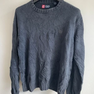 Grå tröja från Chaps - Säljer en stilren grå tröja från Chaps i 100% bomull. Tröjan har en klassisk rund halsringning och långa ärmar. Perfekt för en avslappnad och bekväm stil. Passar bra till både jeans och chinos.