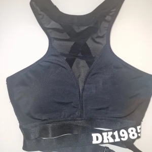Svart sportbh från Hunkemöller  - Snygg sportbh från Hunkemöller  med meshdetaljer och korsade band i ryggen. Använd 1 gång.
