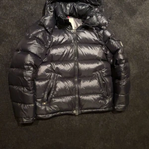 Moncler Maya  - Säljer min moncler maya då vintertiden är över men hoppas på en ny ägare som spar den till nästa säsong, jackan är köpt på Plick och fick den som den var inget OG.Den ända defekten är att det finns ett litet hål i en av fickorna 
